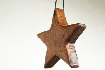 Wooden brown star as a decor element on white wall background copy space for text