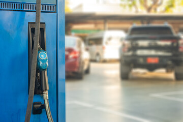 Fuel pump stand with pistol - nozzle, vehicles parking at background
