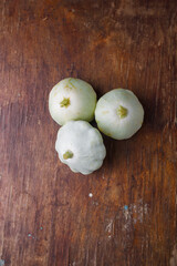Three Patissons, some green pattypan or scallop squashes on old brown wooden rustic table background, top view, copy space