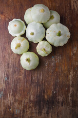 Heap of Patissons, some green pattypan or scallop squashes on old brown wooden rustic table background, copy space. Top view