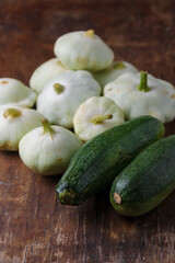 Heap of Patissons, some green pattypan or scallop squashes and zucchini on old brown wooden rustic table background