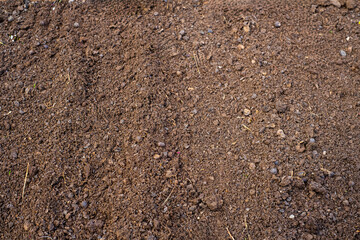 Rich brown soil texture with small stones and organic material for gardening