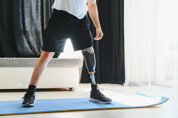 Sporty fit young man amputee with prosthetic leg disability prosthesis doing plank exercise on mat at home. Inclusive sport training for people with disabilities concept