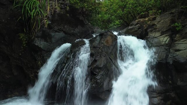 Estrella Waterfall rushing over dark boulders through tropical forest in Narra Palawan with white spray and green vegetation