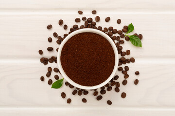 Roasted coffee beans with leaves on wooden background,top view