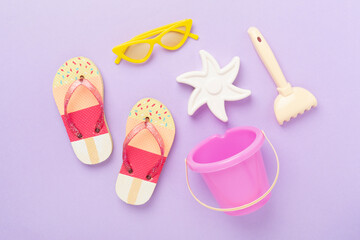 Children's flip flops and beach toys on color background,,top view