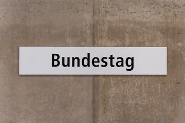Obraz premium A white sign with black letters that says Bundestag. The sign is on a concrete wall