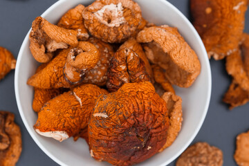 Dried fly agarics in a white cup on a dark background.
