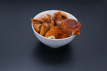 Dried fly agarics in a white cup on a dark background.