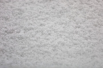 Close-up texture of fresh white snow. Individual snowflakes of various shapes and sizes covering the surface in a continuous layer are visible.