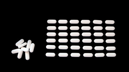 Oval white supplement tablets, arranged neatly in rows, with a small pile on the left. With black background.