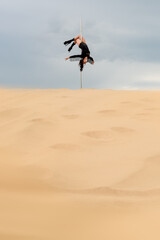 Athletic Pole Dancer in Sand Under Dramatic Sky &mdash; Outdoor Performance Scene with Copy Space