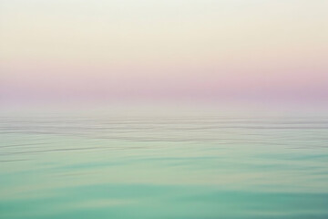 Obraz premium A serene pastel sunrise over a still, tranquil body of water.