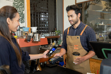 Man owner coffee shop submit an electronic cash register and coffee cup to woman customer, Female...
