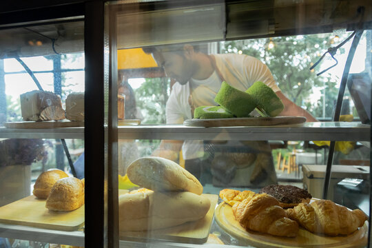 Small business couple lifestyle concept, Asian coffee shop owner man or worker checking online bakery order by using tablet, barista woman making coffee by modern machine, Check stock for sale.