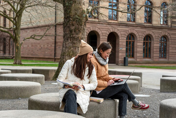 Young women studying in a serene autumn campus park © YesPhotographers