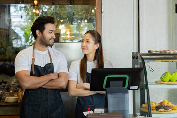 Obraz premium Multiethnic barista couple looking camera happy start-up cafe small business entrepreneur, Indian worker and wife holding laptop technology and tablet for online order and bookkeeping management