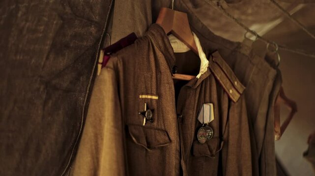 Soviet WWII Junior officer Uniform Jacket with shoulder straps of Lieutenant, military shirt with Medals hangs inside tent. Red Army Gymnastyorka tunic with Order of Red Star replica, Guards Badge