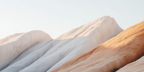 Abstract landscape: ridges in white, gray, and pale orange under soft sunlight and a clear sky.