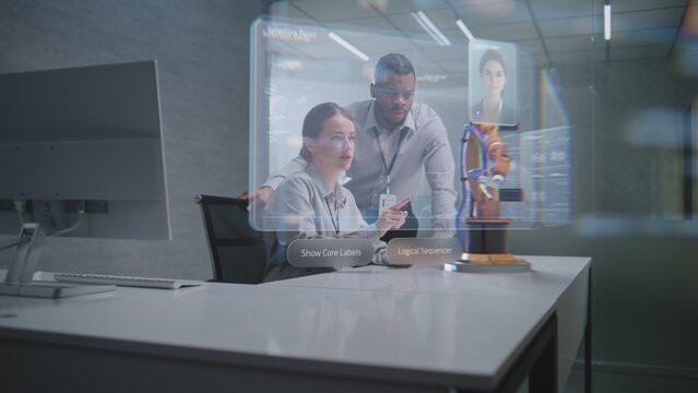 Futuristic Office: Two Diverse Engineers Working on Advanced Robotic Arm Using Augmented Reality Technology. Holographic Interface Display with AI Assistant and Data Analysis. High-Tech Innovation.