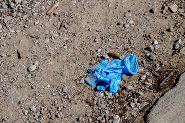 Discarded blue glove on gravel ground