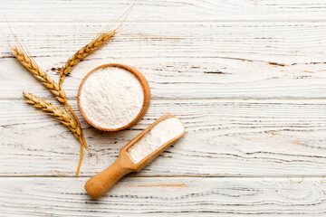 Flat lay of Wheat flour in wooden bowl with wheat spikelets on colored background. world wheat crisis