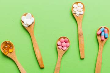 Vitamin capsules in a spoon on a colored background. Pills served as a healthy meal. Red soft gel vitamin supplement capsules on spoon