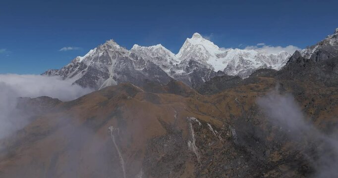Drone rising through clouds, toward snowy peaks of Kanchenjunga Biosphere Reserve