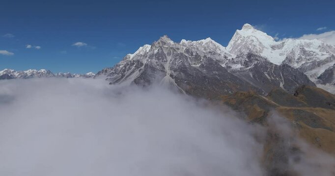 Aerial 360 degree pan shot of mountain tops in middle of clouds, in sunny Nepal