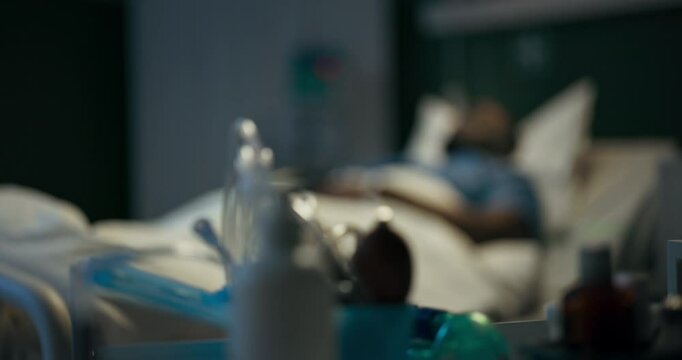 Inside a hospital room, medical supplies are arranged, while in the background, a patient is resting comfortably