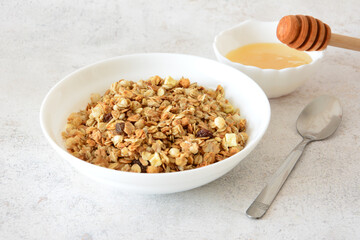 Granola bowl with honey, spoon and a small bowl of honey