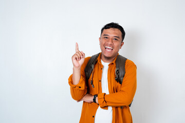 Image of handsome young Asian student wearing backpack pointing with his right hand up on isolated...