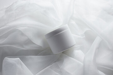 White Cosmetic Cream Jar. Cylinder on textured tan paper with shadows