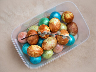 Obraz premium Dyed chicken eggs and a sprig of willow lay on a beige background.