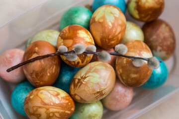Dyed chicken eggs and a sprig of willow lay on a beige background.