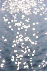 Circular light spots on the water surface. The river in bokeh. Dreamy blue background.