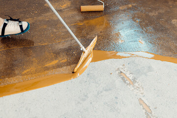 Construction worker applying epoxy resin coating on concrete floor