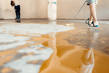 Construction workers applying epoxy resin flooring in a building site