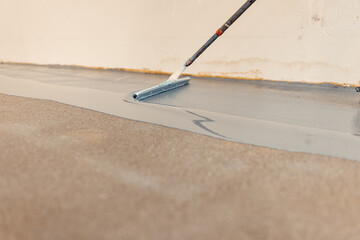 Construction worker applying epoxy resin on concrete floor