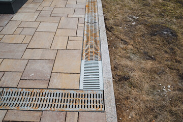 Obraz premium On the sidewalk that runs alongside a vibrant, lush grassy area, there is a drain that serves an essential purpose for effectively managing water runoff in this beautiful outdoor space