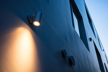 夕暮れの建物の壁を照らすブラケットライト