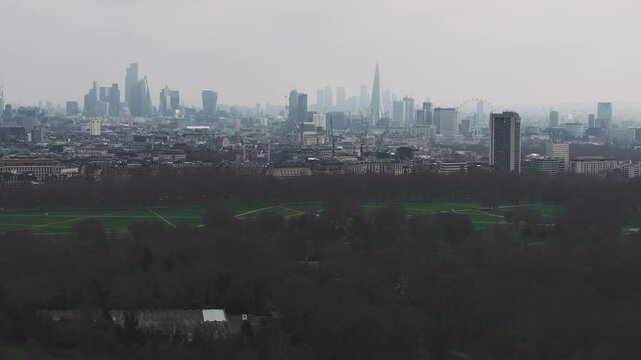 Aerial view of London featuring the Shard, Walkie Talkie, and a large park. The camera pans across the skyline under an overcast sky.