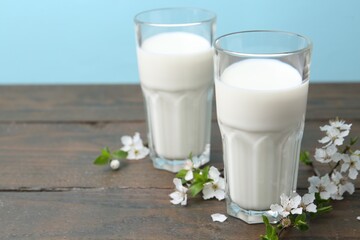 Fresh milk and blossoms on white table against light blue background