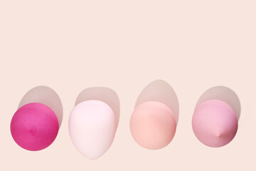 Makeup sponges arranged on a pastel pink background