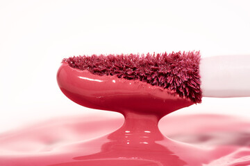 Macro shot of a lip gloss applicator covered in a rich, glossy pink product