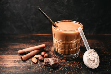 Healthy protein milkshake in a glass with a straw, a measuring scoop of whey protein powder,...