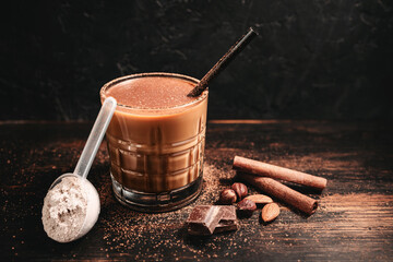 Healthy protein milkshake in a glass with a straw, a measuring scoop of whey protein powder,...