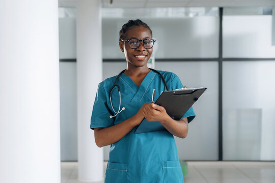 Black notepad in hands. Female doctor is indoors in modern room