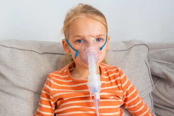 Young child using asthma inhaler at home while sitting on a couch during a calm afternoon