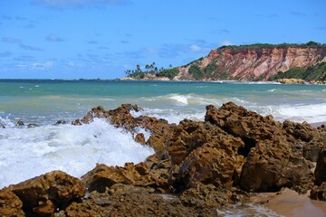 Tabatinga beach close to Joao Pessoa city, Paraiba state, Brazil northeast. Tropical seascape with waves crashing on rocks, blue sea, coloroful cliffs on horizon line. Toutistic place 